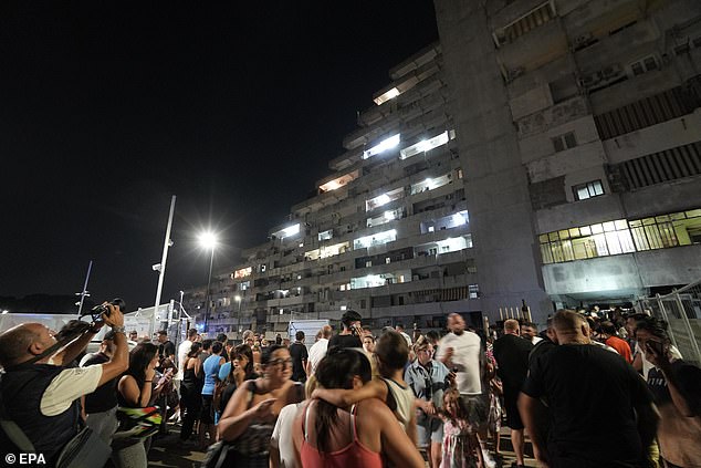 People evacuated from their apartments watch as a balcony collapses in the Vela Celeste housing complex in Scampia, Naples