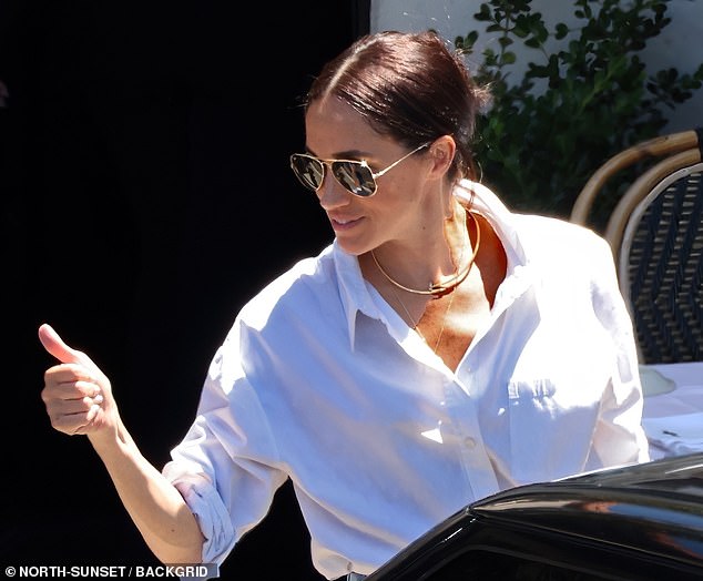 Meghan, who is pictured giving Kimberly a thumbs up, has previously been spotted wearing her £15,500 Cartier necklace