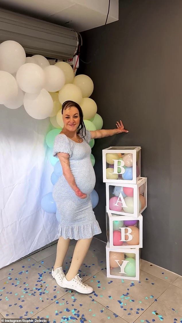 The expectant mother changed into a tight blue dress to indicate the baby's gender, and held her baby bump tightly as she posed next to the baby blocks