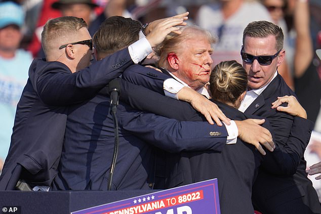 Republican presidential candidate and former President Donald Trump is surrounded by US Secret Service agents after being shot at rally in Butler