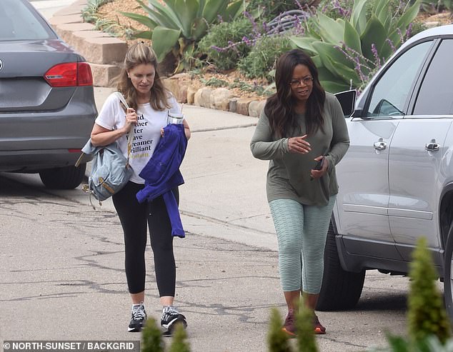 Oprah looked slim in a gray-green long-sleeved shirt that hung loosely around her