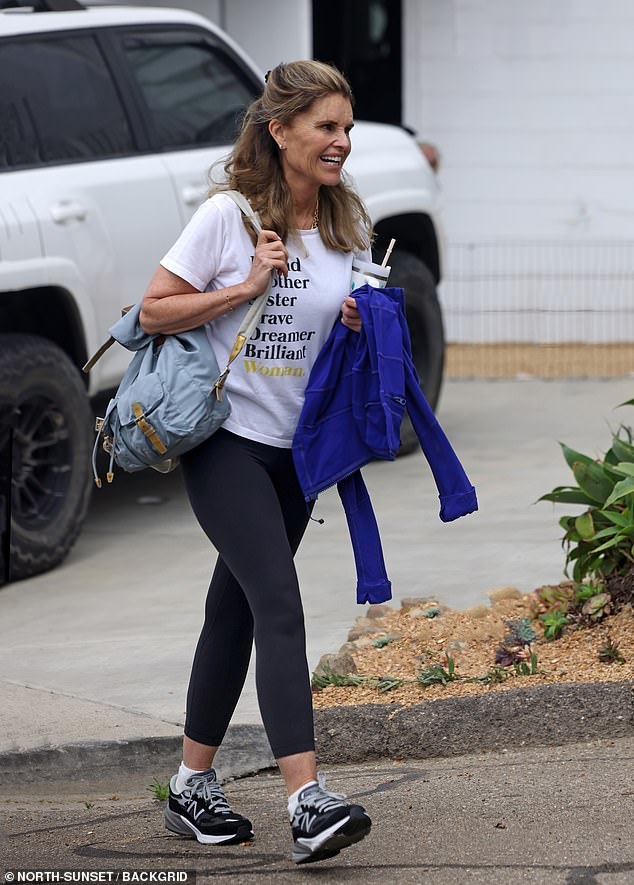 She looked comfortable in black, white and gray New Balance sneakers and her arms were full of a powder blue bag, a royal blue jacket and a large water bottle