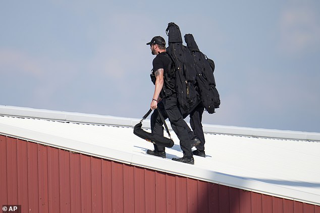 Police snipers walk on a roof to set up before Republican presidential candidate and former President Donald Trump speaks during a campaign rally in Butler, Pennsylvania, Saturday, July 13, 2023