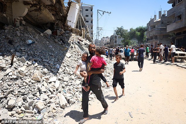 A man carries children as people inspect the damage after the Israeli bombardment of the al-Bureij refugee camp in the central Gaza Strip on July 23, 2024