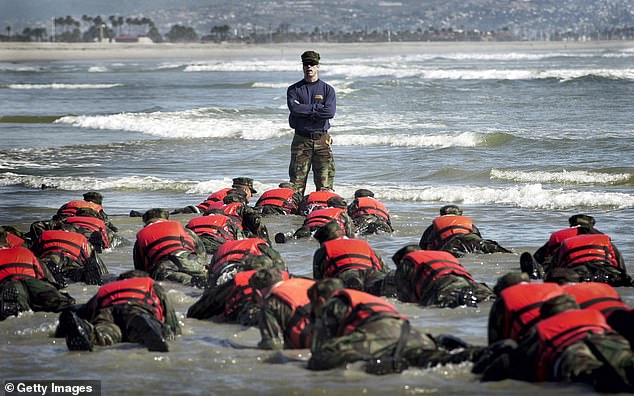 A Navy SEAL instructor helps Basic Underwater Demolition/SEA students