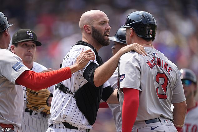 Colorado Rockies catcher Jacob Stallings, center, stands between starting pitcher Cal Quantrill, left, and Boston Red Sox forward Reese McGuire