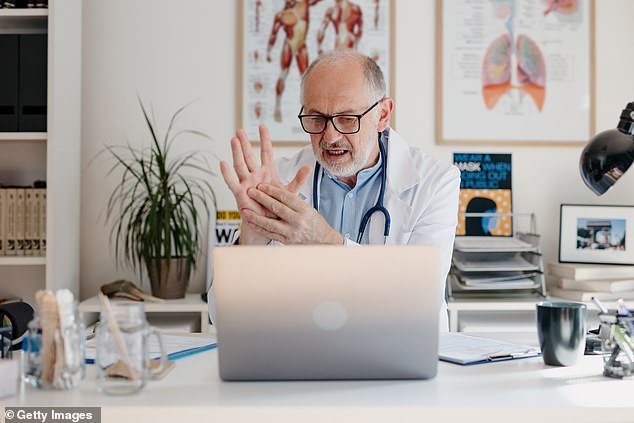 A doctor is having a video call with a patient while sitting in his office (stock image)