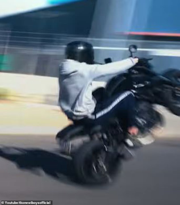 The music video shows motorcycles doing wheelies (pictured) and cars doing burnouts on a road in an industrial area