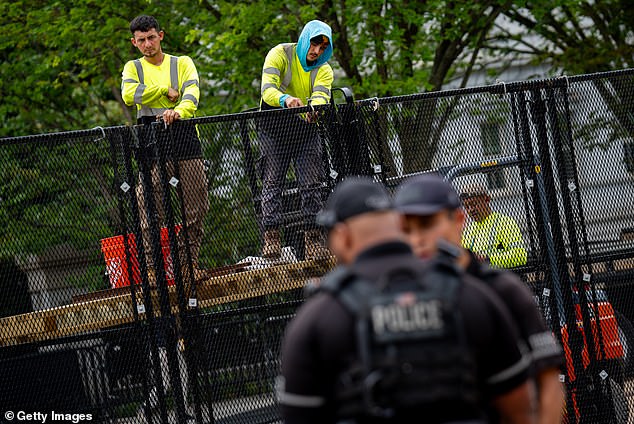 Secret Service members stand guard as employees install additional security fencing around the White House