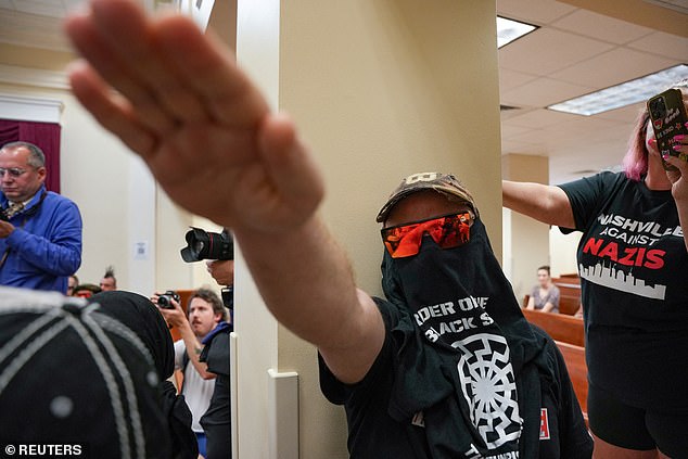 A member of the Goyim Defense League makes hate gestures while disrupting a city council meeting in Nashville