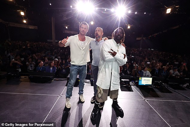 Hemsworth took the stage in Hall H of the San Diego Convention Center wearing a white T-shirt under a white short-sleeved shirt and a long gold chain.