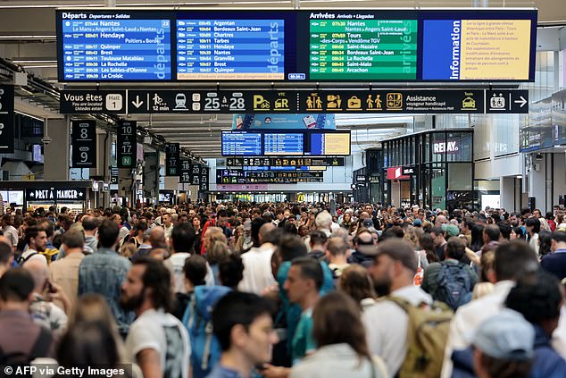 Passengers gather around departure boards at Gare Montparnasse train station in Paris on July 26, 2024, as France's high-speed rail network was hit by malicious acts that disrupted the transport system, just hours before the opening ceremony of the Paris 2024 Olympic Games.