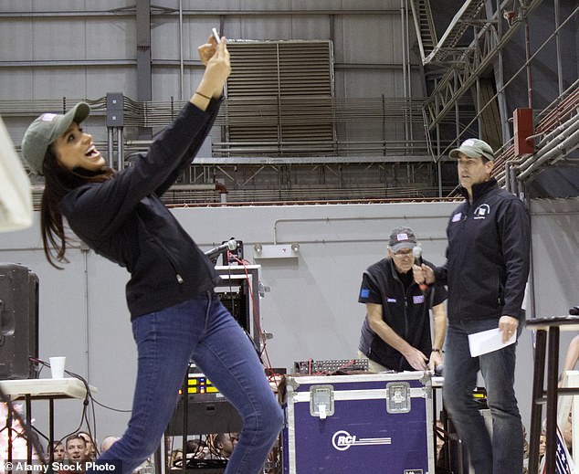 Meghan Markle, left, takes a selfie with the crowd of soldiers as comedian Rob Riggle looks on during the USO Holiday troops visit at Bagram Air Field on Dec. 9, 2014 in Afghanistan