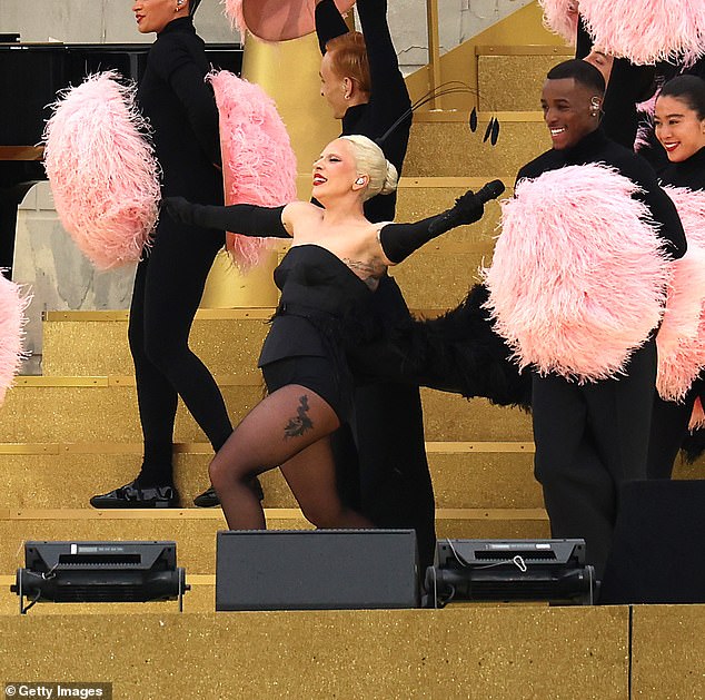 She was accompanied by a whole group of dancers dressed in black and waving pink feathers during the spectacular performance