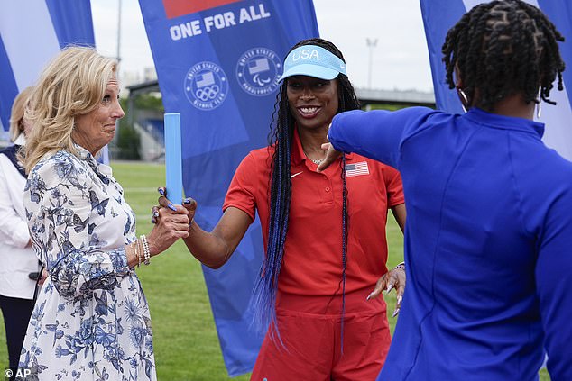 Jill Biden, left, learns the proper technique for passing a baton from women's relay head coach Mechelle Freeman, center