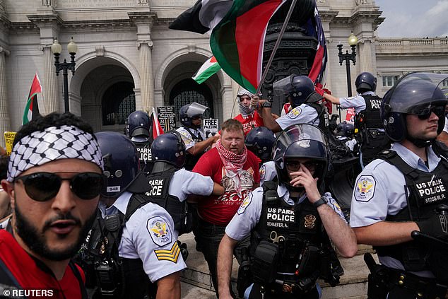 Police officers attempt to stop pro-Palestinian protesters from taking down an American flag outside Union Station