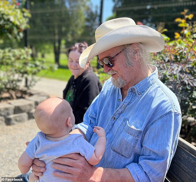 The guitarist and singer wore a loving gaze as he held one of his five grandchildren