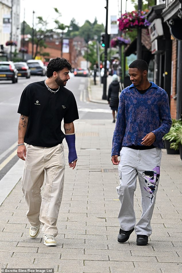 Sam wore a casual black T-shirt and cargo pants, while Roman wore a patterned sweater