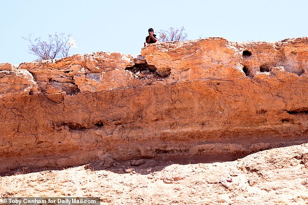 A young smuggler hides his face after seeing DailyMail.com's camera take a picture of him