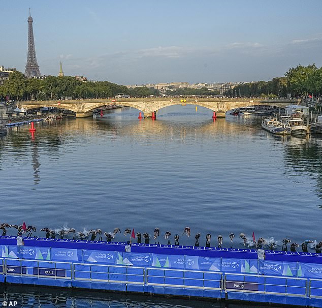 Athletes dive into the Seine from the Alexander III Bridge at the start of the first leg of the women's triathlon test event for the 2024 Paris Olympics