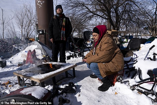 However, fewer affordable homes are being built, meaning rising prices have forced many onto the streets. Cyrus Whittaker, left, and Debbie Orca sit around a fire in the homeless camp where they live during record-breaking cold and snow in Oklahoma City on Feb. 16, 2021