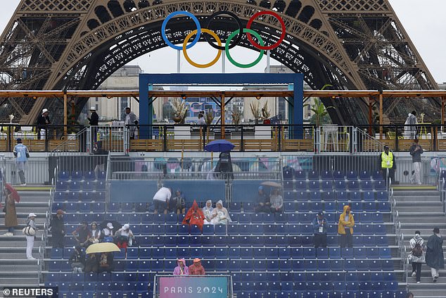 Fans wear raincoats as they wait for the opening ceremony to begin