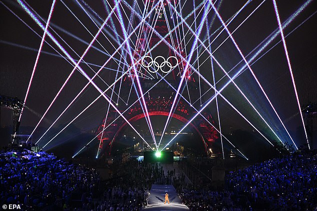 Multi-colored laser beams tear open the rusty shell of the Eiffel Tower during the opening ceremony