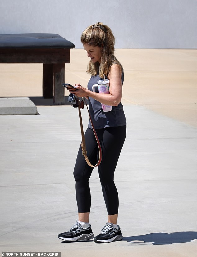 The former First Lady of California, 68, was similarly dressed in a gray tank top and black leggings with the beach in the background as she looked down at her phone and carried a Stanley cup under her arm