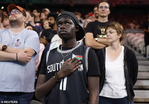 A confused South Sudanese fan stands up during the playing of another national anthem