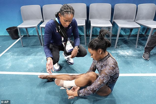 Biles gets her ankle taped after an uneven bars match during the qualifying round