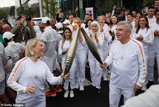 Emma Terho, President of the IOC Athletes' Commission, and Thomas Bach, President of the International Olympic Committee (IOC), carry the Olympic flame on July 26