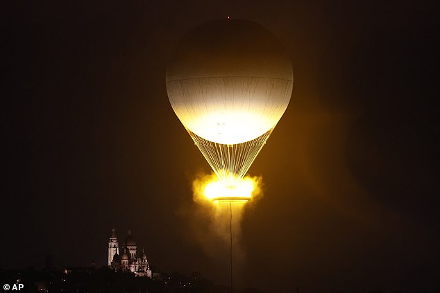 The cauldron, containing the burning Olympic flame, rises while attached to a balloon