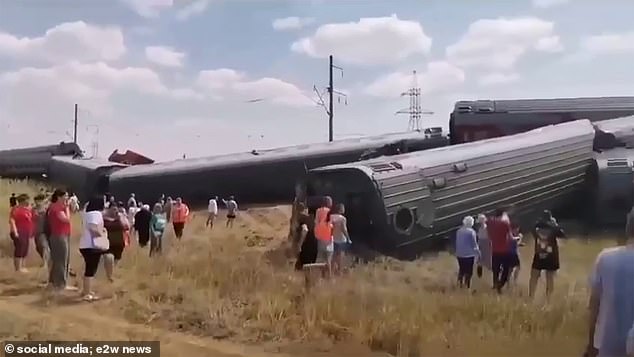 Shocked bystanders gather around the train as people rush to help those trapped inside