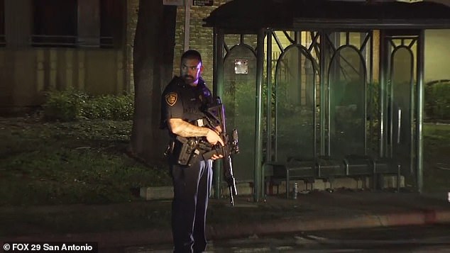 An armed police officer stands guard after three officers were shot while responding to a domestic violence report in San Antonio Sunday morning