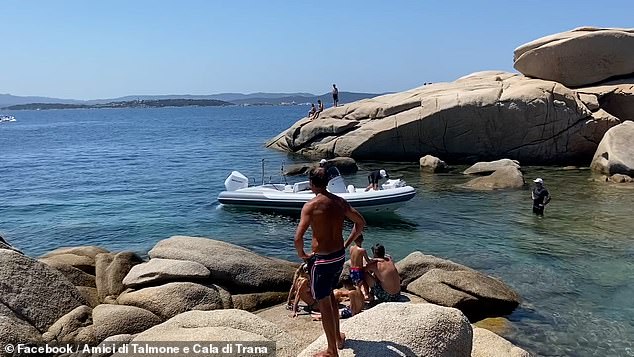 Beachgoers watch as members of the Italian coast guard arrive to end the party