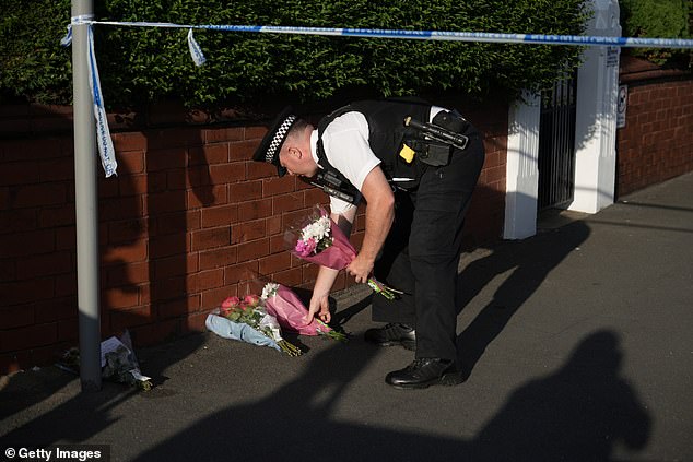 A police officer lays flowers at the scene of a multiple stabbing