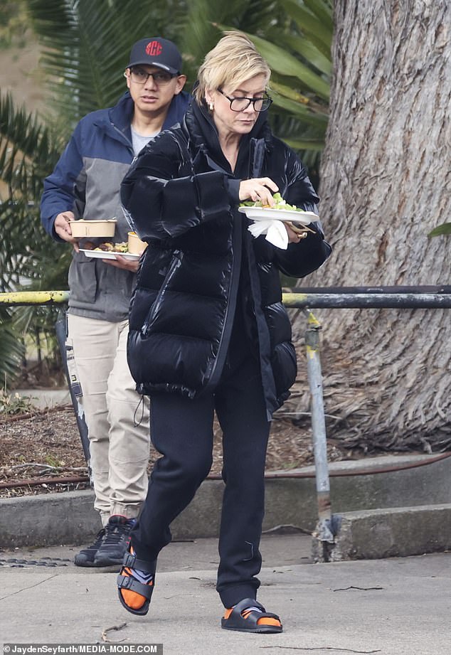 She braved the cold and kept warm in a black puffer jacket over another fleece, plus black sweatpants and bright orange socks, worn with black Birkenstock sandals