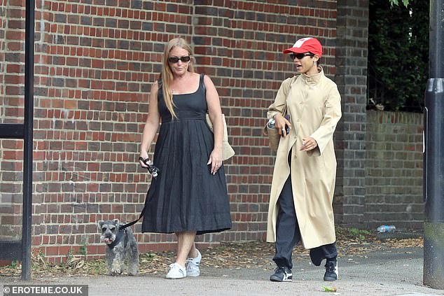 She wore her beige trench coat buttoned up and completed the look with comfortable black and white sneakers