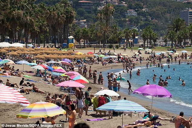 Beachgoers sunbathe on Malagueta Beach on a hot summer day in Malaga