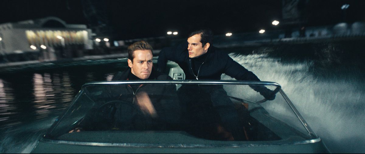 CIA agent Napoleon Solo (Henry Cavill) and KGB agent Illya Kuryakin (Hammer), both dressed in black, stand together in a speedboat at night during a mission in The Man From U.N.C.L.E.