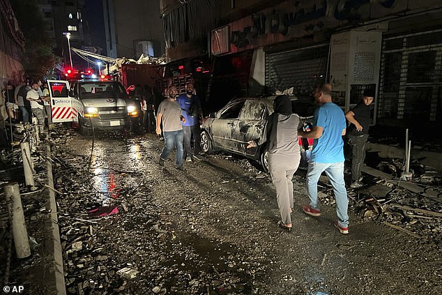 People walk near the building hit by an Israeli airstrike in the southern suburbs of Beirut