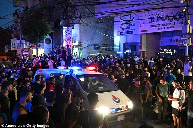 An ambulance makes its way through the crowd. Tonight, video footage showed an apartment building on fire and a sense of panic in the southern suburb of Haret Hreik