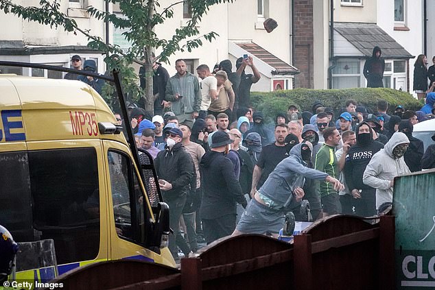 Rioters wearing masks fire missiles at police officers in Southport