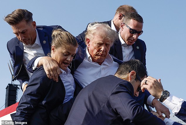 Former President Trump is helped off the stage after being shot during a campaign speech in Butler, Pennsylvania