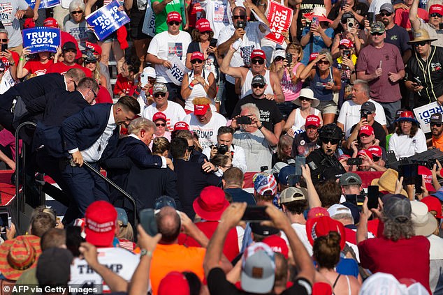 Republican candidate Donald Trump is surrounded by Secret Service agents with blood on his face as he is escorted off stage during a campaign event at Butler Farm Show Inc. in Butler, Pennsylvania, July 13, 2024. The suspected gunman who wounded Republican presidential candidate Donald Trump at a rally has died, U.S. media reported Saturday, along with a bystander