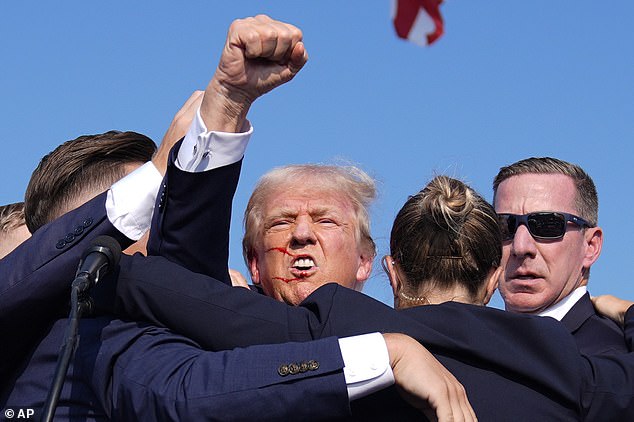 Trump clenches his fist as he is surrounded by Secret Service agents