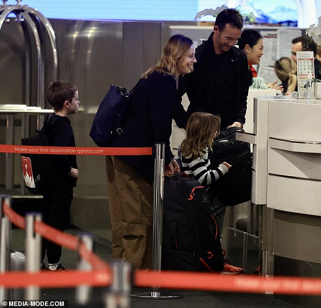 Arriving at the Qantas business class check-in desk, Ally travelled in style in a smart pair of brown trousers and a black T-shirt, which she teamed with a tailored jacket