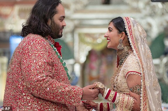 In this photo provided by Reliance Industries, Anant Ambani (L), the son of billionaire Mukesh Ambani, holds hands with Radhika Merchant during their wedding ceremony at the Jio World Convention Centre in Mumbai, India, Friday, July 12, 2024. (Reliance Industries via AP)