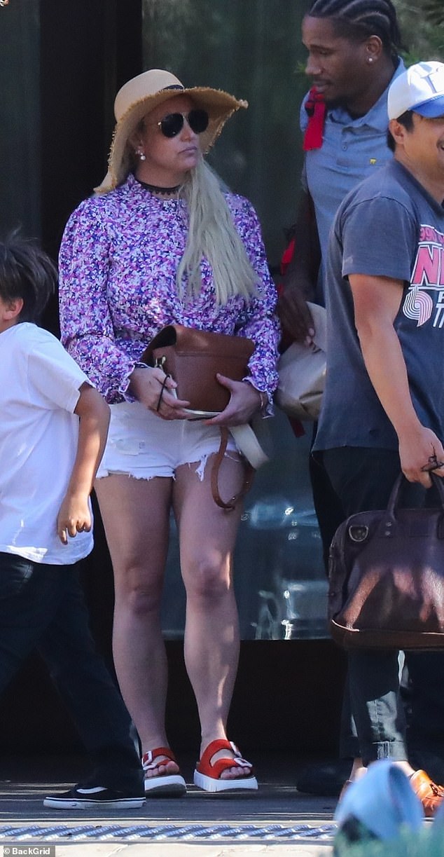 Britney looked casual in a purple and white top with white jeans, accessorized with a straw hat and slip-on sandals