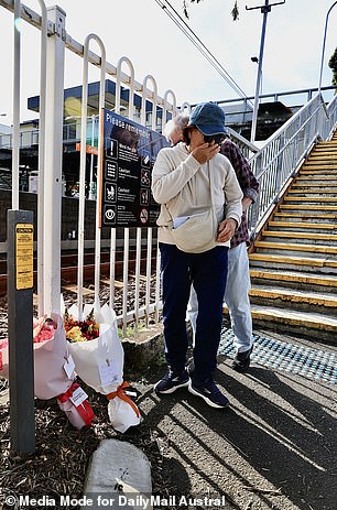 The photo shows a member of the public laying a floral tribute at Carlton train station